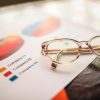 Close-up of eyeglasses on a table with colorful business charts.